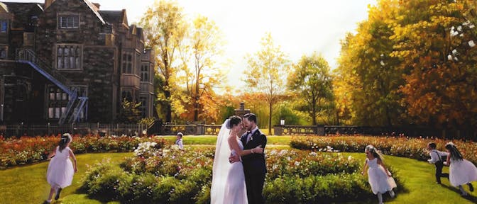 A couple on their wedding day embracing in a garden with kids playing around them.