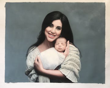 A mother holding her newborn baby on a plain background.