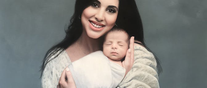 A mother holding her newborn baby on a plain background.